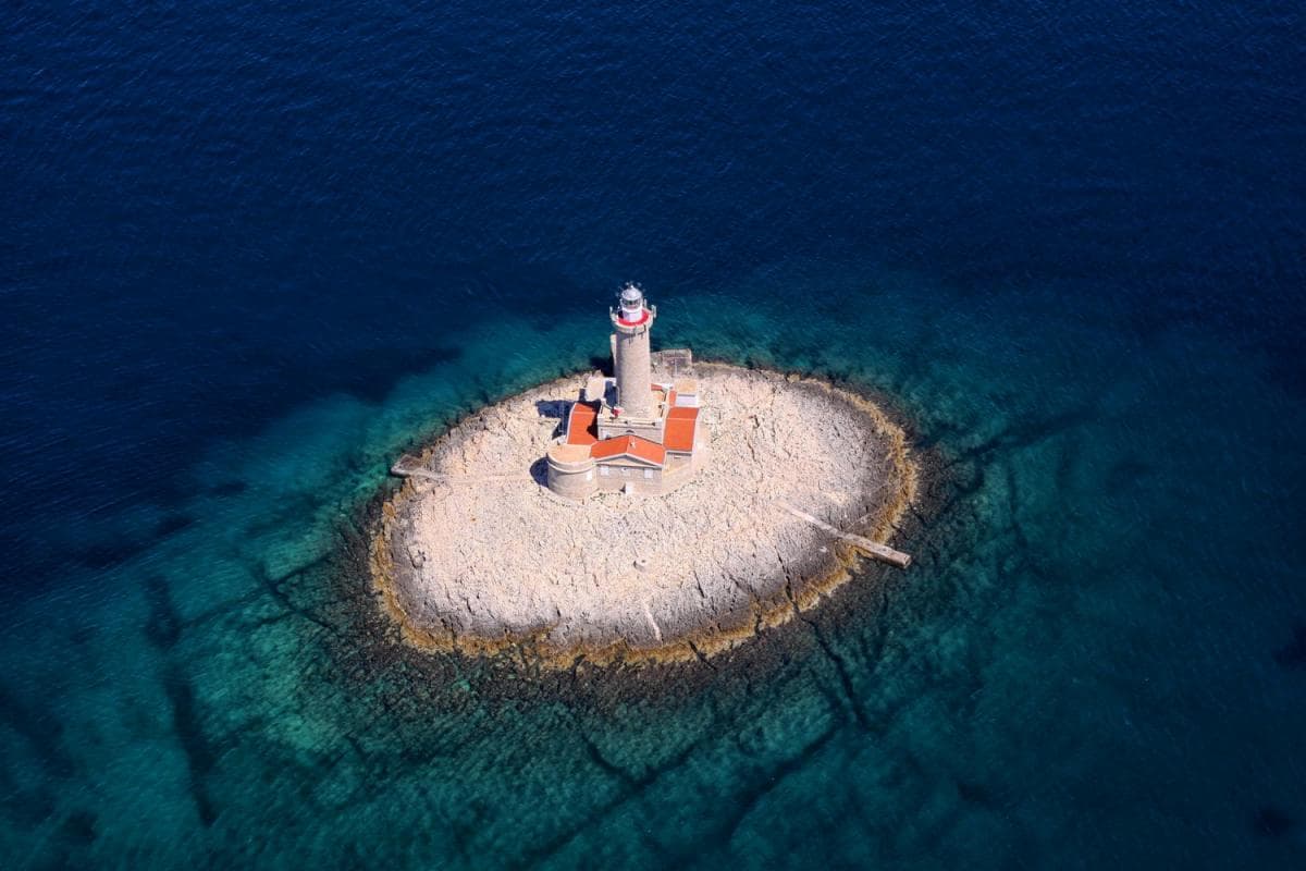 Porer lighthouse on a small islet off Cape Kamenjak in southern Istria, surrounded by open Adriatic sea.