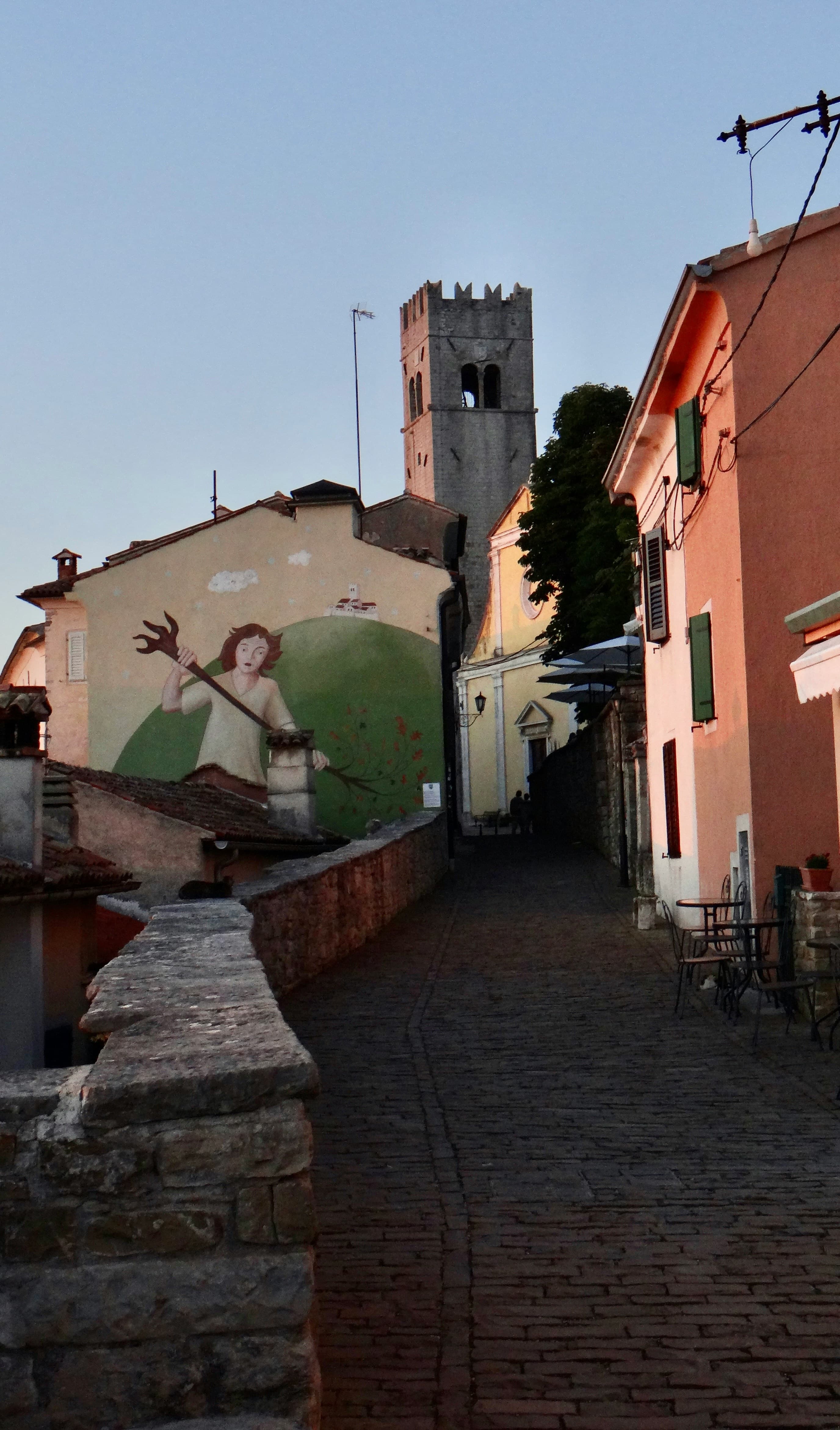 Narrow cobbled street in Motovun with stone buildings and arched passageways leading toward the church