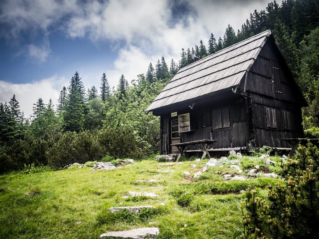 A traditional dark-timber mountain hut among pines on a stone meadow — the kind of base used by walkers staying inside the Velebit.