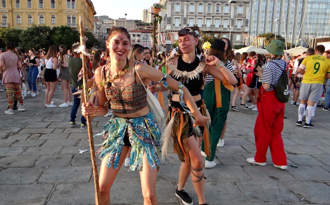 Danzatrici in costume sfilano lungo il Korzo durante il Carnevale di Rijeka, con la folla che fiancheggia il percorso.