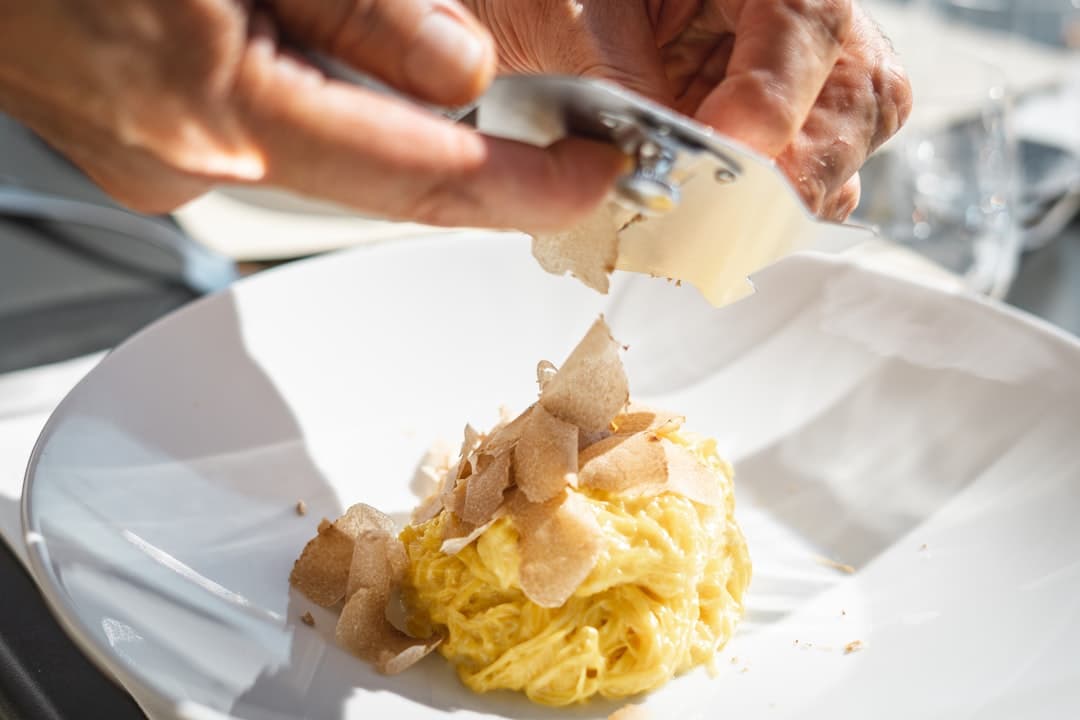 Tartufo bianco fresco affettato a mano su un piatto di tagliatelle al rosso d'uovo — il piatto centrale di ogni festival del tartufo istriano.