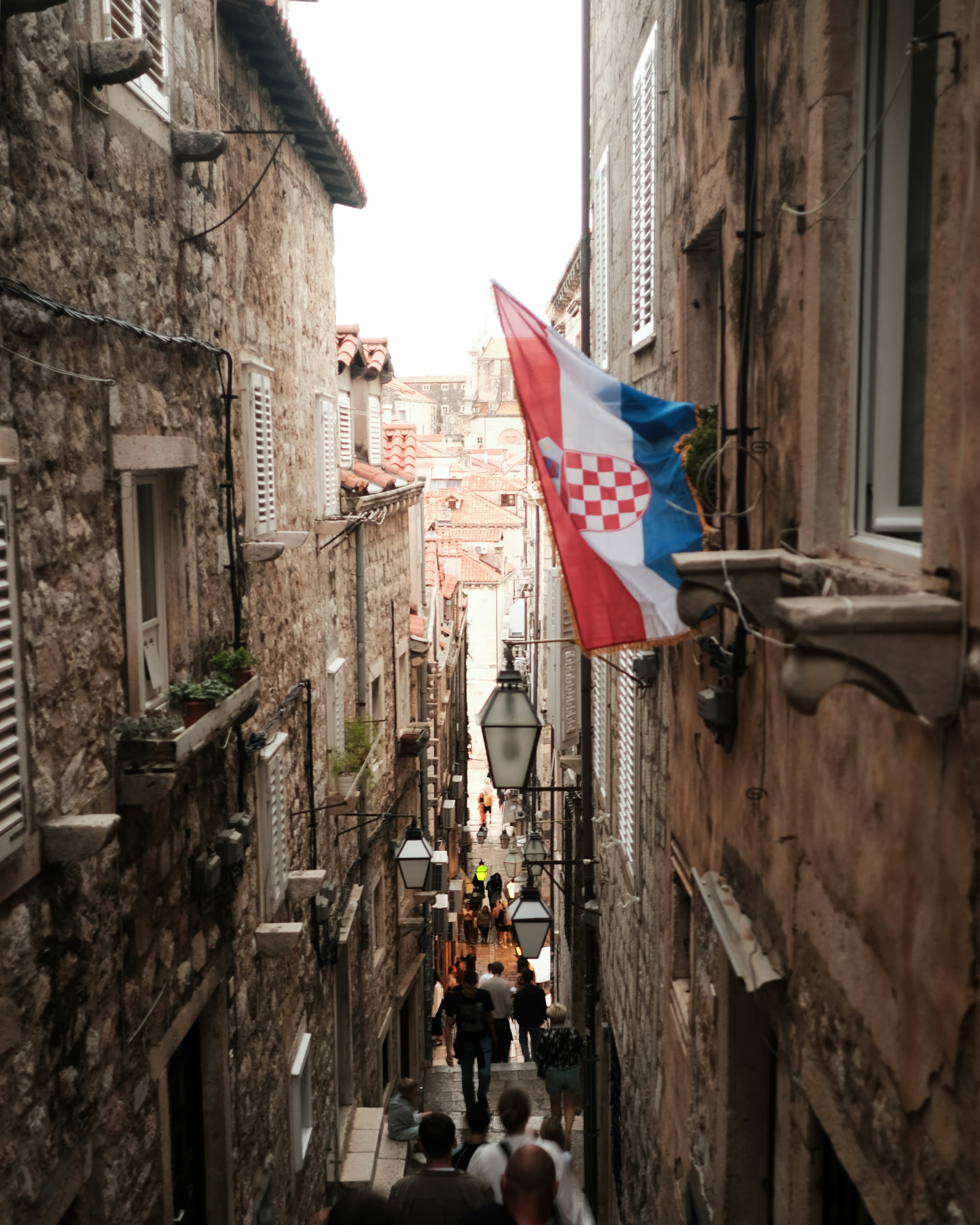 A Croatian flag above a narrow stone lane in Dubrovnik