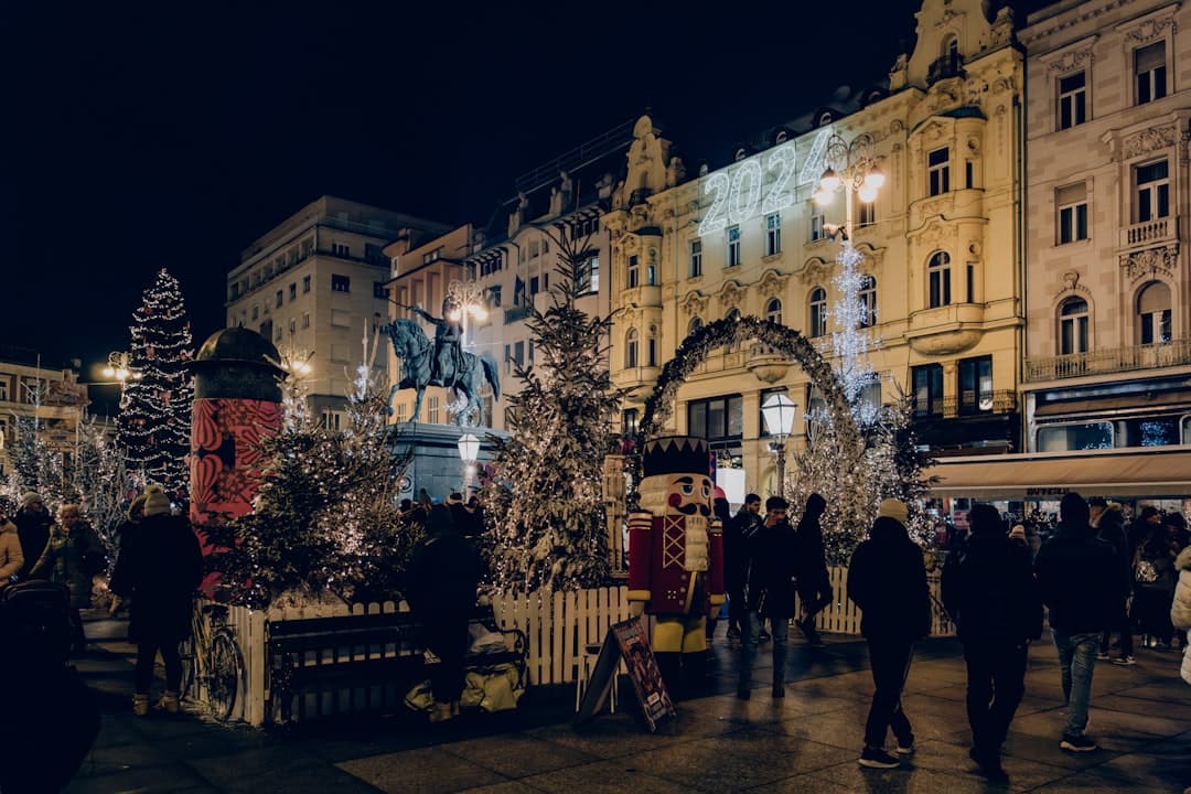 Besucher versammeln sich um einen beleuchteten Weihnachtsbaum und eine festlich geschmückte Straßenbahn auf dem Ban-Jelačić-Platz während des Advents in Zagreb.