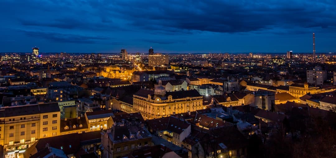 Eine Luftaufnahme von Zagrebs Unterstadt in der Abenddämmerung — die Lichter der Plätze und Dächer ziehen sich bis zur Kathedrale.