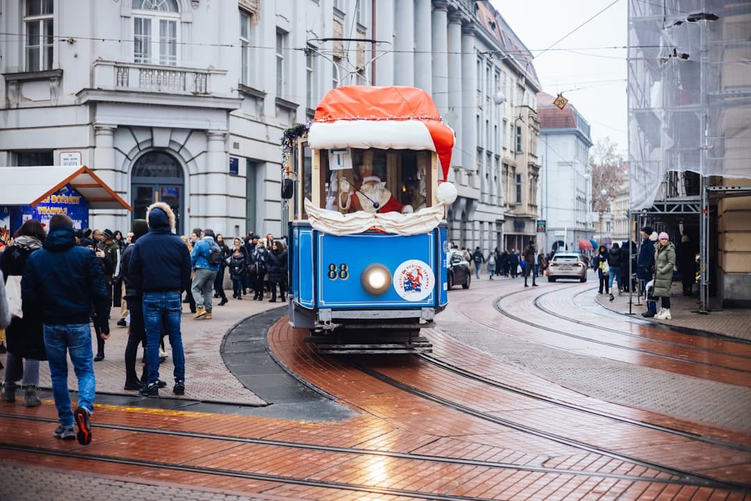 Zagrebs festliche Weihnachtsstraßenbahn in Rot-Weiß, mit Fahrern als Weihnachtsmänner verkleidet, im Stadtzentrum.