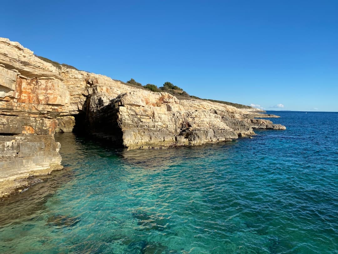 Una scogliera di calcare bianco osseo si erge sull'Adriatico blu profondo — la geologia carsica che definisce Capo Kamenjak.