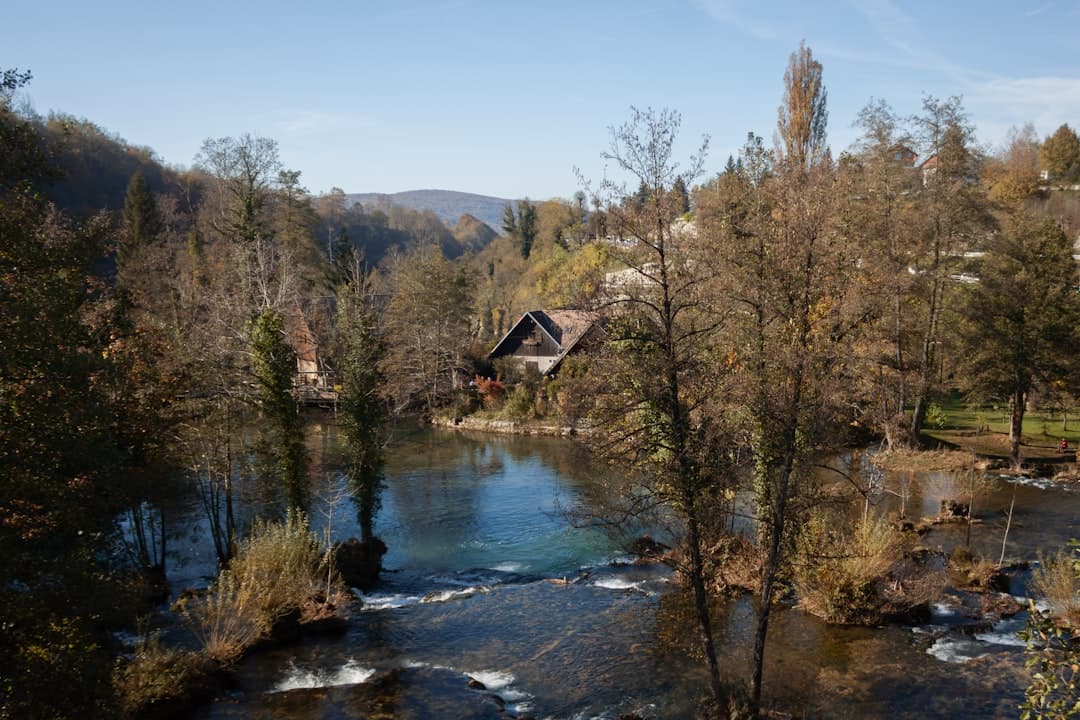 Late-winter view of the Korana river curving past bare trees and a single mill house, illustrating the Zagreb–Plitvice approach to Slunj.