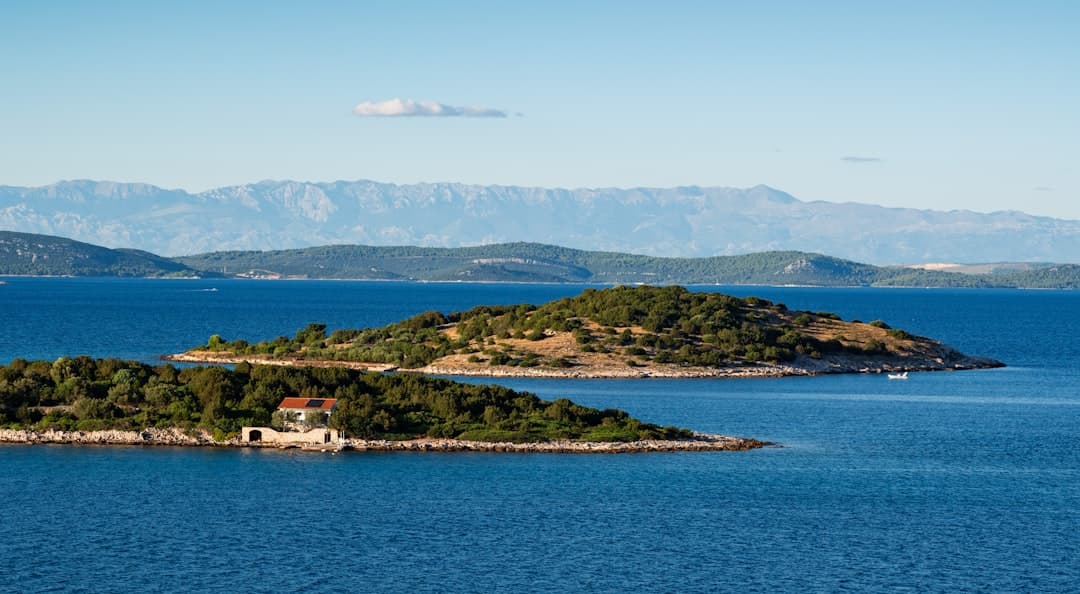 Two pine-covered islets in calm Adriatic water — the kind of sheltered channel that makes the Elafiti chain near Dubrovnik so paddler-friendly.