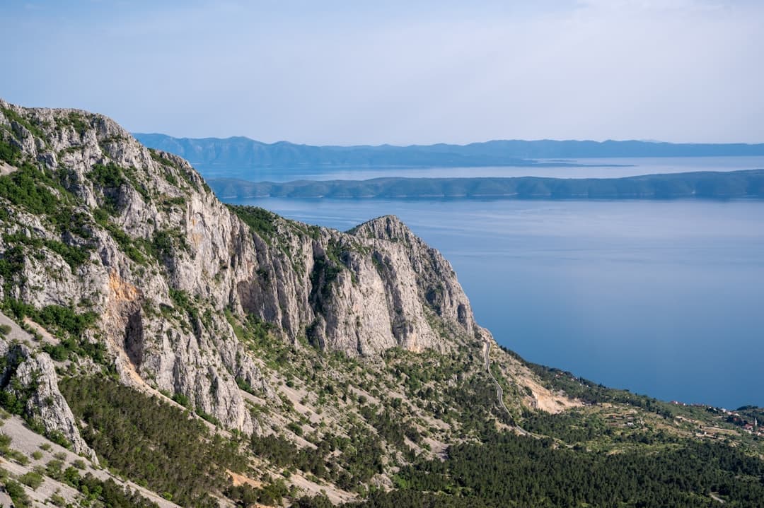 A sheer limestone cliff face dropping into deep Adriatic water, evoking the 161-metre Stene cliffs on Dugi Otok's open-sea side.